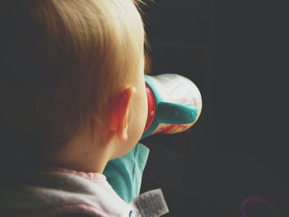 Un niño beb leche de un biberón.