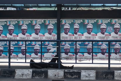 Un hombre durmiendo en la calle bajo los carteles electorales en Lagos, Nigeria, este martes.