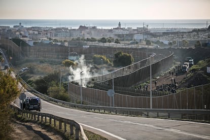 Las fuerzas de seguridad vigilan el perímetro fronterizo de Melilla, este jueves, mientras cientos de inmigrantes aguardan en el lado marroquí.