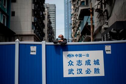 Un hombre con mascarilla subido en una barricada que impedía la entrada a un complejo residencial en Wuhan, el 14 de abril de 2020.