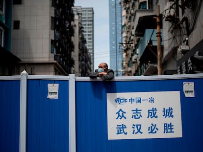 Un hombre con mascarilla subido en una barricada que impedía la entrada a un complejo residencial en Wuhan, el 14 de abril de 2020.