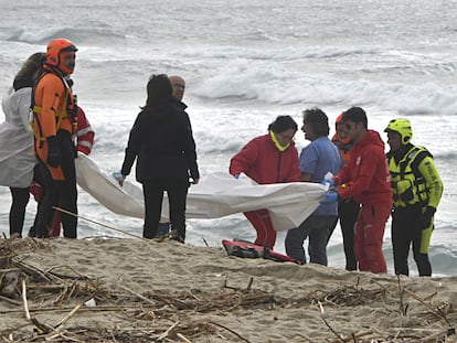Un equipo de rescate, con una lona para cubrir alguno de los cuerpos de migrantes llegados a la costa tras un naufragio frente a la costa de Calabria, este domingo.