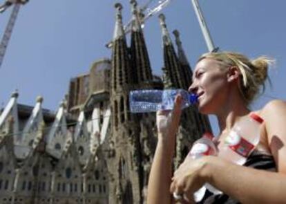 Una turista bebe agua ante la basílica de la Sagrada Familia de Barcelona. EFE/Archivo