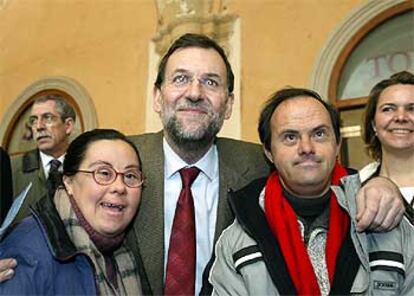 El candidato popular Mariano Rajoy se fotografía junto a dos personas con síndrome de Down.