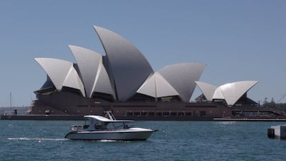 Un barco de recreo llega a la zona de atraque en la Bahía de Sidney. Al fondo, el edificio de la ópera.