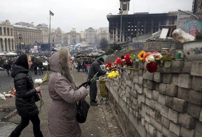 Dos mujeres depositan flores en una pared en la Plaza de la Independencia en homenaje a los caídos por los enfrentamientos de los últimos días, en la plaza de la Independencia de Kiev, 22 de febrero de 2014. 