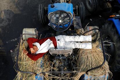 El hijo de un granjero duerme en un tractor durante la protesta contra las nuevas leyes agrícolas, en la frontera entre Delhi y Uttar Pradesh en Ghaziabad (India).