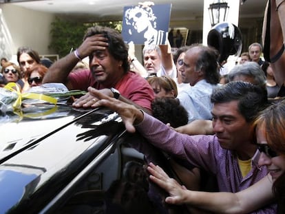 Aficionados del fallecido m&uacute;sico argentino Luis Alberto Spinetta siguen el coche con su at&aacute;ud, tras su funeral.