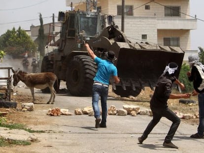 Palestinos lanzan piedras a un bulldozer en la villa de Kafr Qaddum, cerca de Nablus, en Cisjordania.