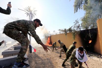 Los manifestantes han quemado banderas estadounidenses y arrancado las cámaras de seguridad, después de que las fuerzas especiales de seguridad de Irak se desplegaron delante de las puertas del edificio para impedir la entrada. En la imagen, un grupo de milicianos prende fuego este martes al muro de las instalaciones de la Embajada de EE UU.