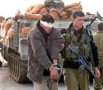 Un soldado israelí guía a un palestino detenido en la <i>operación de limpieza</i> realizada en Beit Hanun, al norte de Gaza.