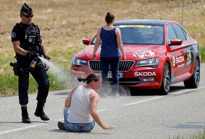 Un antidisturbios fumiga con gas pimienta a una campesina para abrirle paso a un coche del Tour.