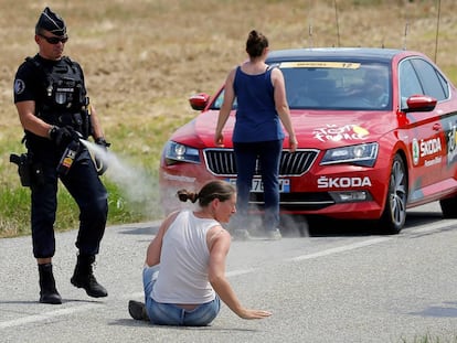 Un antidisturbios fumiga con gas pimienta a una campesina para abrirle paso a un coche del Tour.