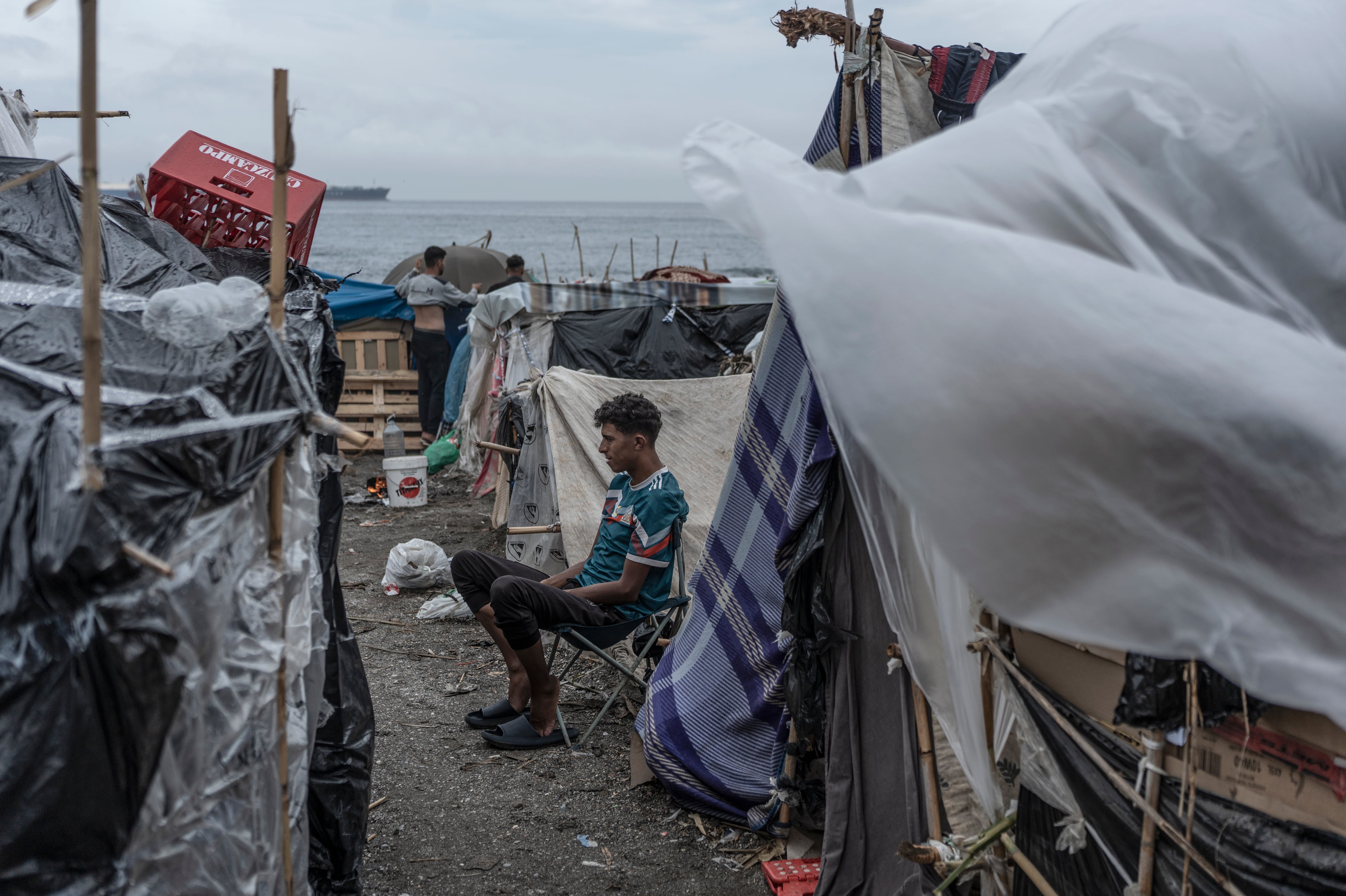 Tras las lluvias de la noche y de la mañana, un joven migrante marroquí sentado frente a su tienda improvisada en la playa del Trampolín en Ceuta, España, el 27 de septiembre.