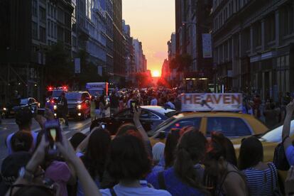 El sol se esconde tras los edificios ante la mirada de los transeúntes que intentan fotografiar el peculiar atardecer.