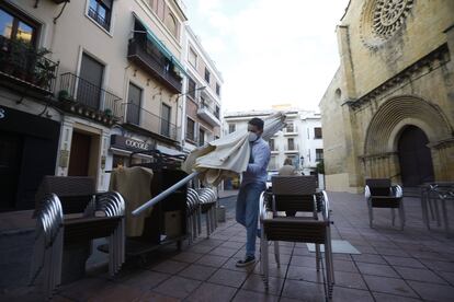 Un trabajador recoge el mobiliario de la terraza de un restaurante en el centro de Córdoba.EFE/Salas