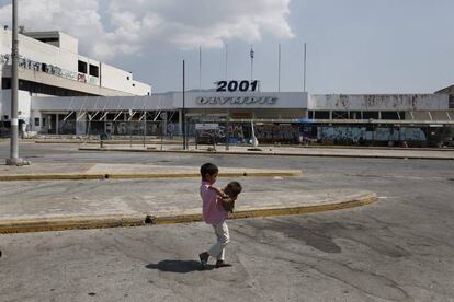 Un ni&ntilde;o afgano lleva en brazos a su hermano en los alrededores del antiguo aeropuerto de Atenas.