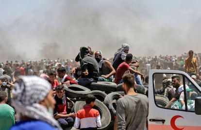 Um grupo de palestinos tenta incendiar pneus durante os confrontos contra as tropas israelenses perto da Faixa de Gaza.