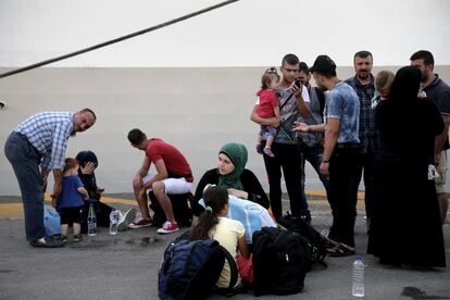 Refugiados e inmigrantes esperan para subir a un autobús después de su llegada al puerto de El Pireo desde Siria