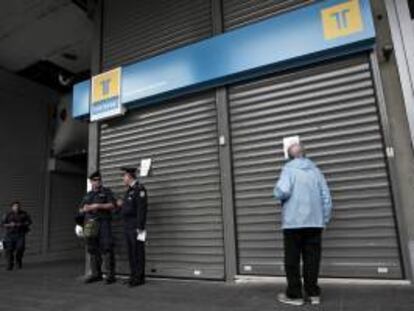 Dos policías hacen guardia junto a una sucursal bancaria cerrada el pasado miercoles, día en el que los empleados de la banca griega se manifiestaron en Atenas contra las medidas de austeridad impuestas por el gobierno heleno.