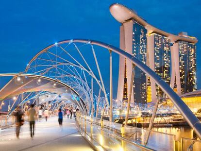 Paseantes en el puente Helix, en Singapur, con el famoso hotel Marina Bay Sands al fondo.