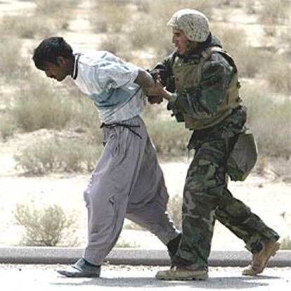 Un <i>marine</i> arresta a un soldado iraquí, vestido con ropa de civil, en el camino al norte de la ciudad de Basora.