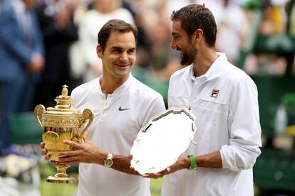 Roger Federer y Marin Cilic sujetan sus trofeos tras la final de Wimbledon.