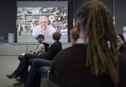 Participantes atienden al discurso que el fundador de Wikileaks, Julian Assange (en la pantalla), pronunció vía Skype desde la embajada de Ecuador en Londres, donde permanece refugiado desde el pasado mes de junio, durante la conferencia de internet llamada "Convention Camp" en Hanover, Alemania.