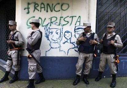 Paraguayan police stand near graffiti accusing Franco of staging a coup.