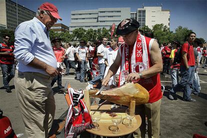 Dos seguidores del Sevilla se disponen a degustar un jamón.