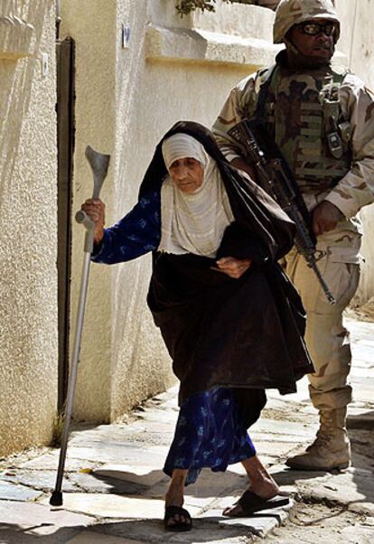 Una mujer camina por una calle de Bagdad delante de un soldado de EE UU.
