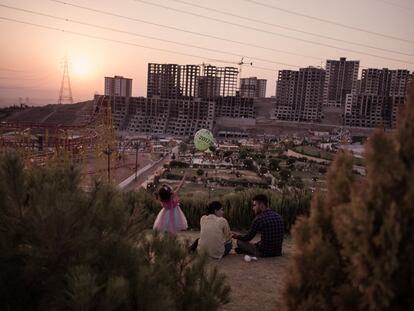 Una familia disfruta de un pícnic en el parque de atracciones Chavy Land mientras el sol se pone detrás de un edificio en construcción. La población de Solimania se ha multiplicado en los últimos años gracias al clima templado de la zona y a su cercanía a las montañas.