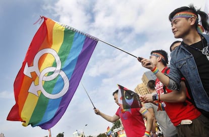 Un hombre porta la bandera arcoiris en una manifestación en Taipei.