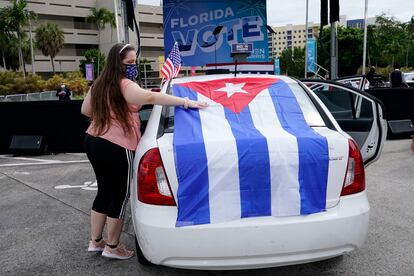 Una mujer pone una bandera cubana en su coche, en un mitin de Biden en Miami.