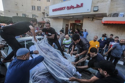 Varios palestinos trasladaban cadáveres en las afueras del hospital Mártires de Al Aqsa, este martes en Deir al Balah.