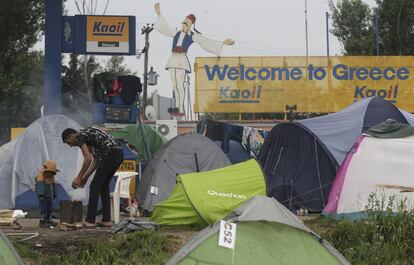 Un refugiado y un niño se calientan junto a una hoguera al lado de las tiendas de campaña junto a una gasolinera cerca de la aldea de Idomeni.