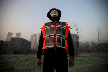 El artista Liu Bolin, porta una mascarilla y un chaleco con 24 teléfonos móviles adheridos a él, emite en directo vía internet, la contaminación del aire en la ciudad, en Pekín (China).