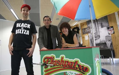 Los hermanos responsables de A Fuego Negro, Edorta Lamo y Amaia García de Albizu, y el director del BCC, Joxe Mari Aizega (centro), posan junto al carro desde el que en verano venden 'flashes' de gazpacho.