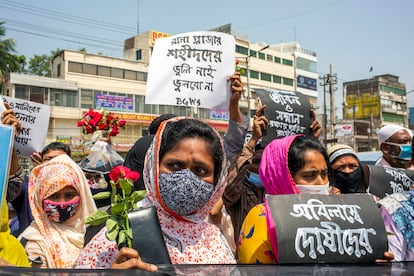 Miembros de una organización de derechos laborales sostienen pancartas y flores para rendir homenaje a las víctimas en el lugar donde estuvo el edificio Rana Plaza en las afueras de Dacca, Bangladés, 24 de abril de 2021, octavo aniversario del desastre.