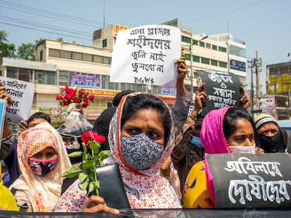 Miembros de una organización de derechos laborales sostienen pancartas y flores para rendir homenaje a las víctimas en el lugar donde estuvo el edificio Rana Plaza en las afueras de Dacca, Bangladés, 24 de abril de 2021, octavo aniversario del desastre.