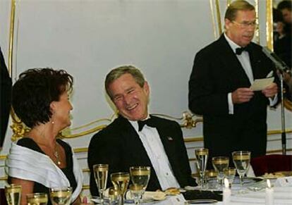 George Bush bromea con Jolanta Kwasniewski, la esposa del presidente polaco, mientras el presidente checo, Vclav Havel, lee su discurso en la cena de gala.