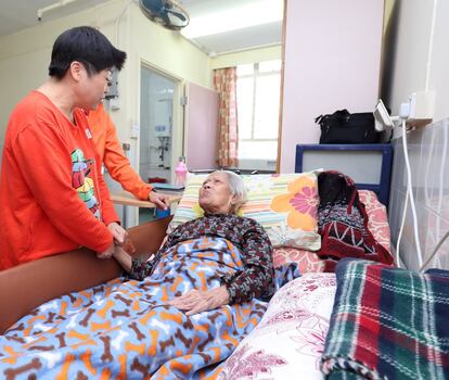 La señora Chan es atendida por dos voluntarios en la residencia de cuidados paliativos, que la fundación La Caixa y la fundación BEA sostienen en Hong Kong