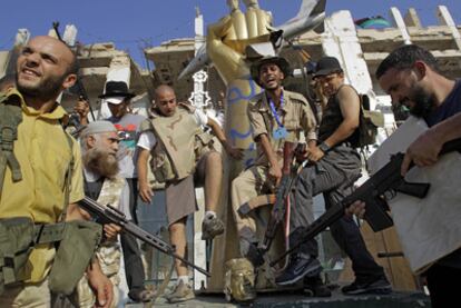 Insurgentes apuntan a la cabeza de una estatua de Gadafi en Bab el Azizia.