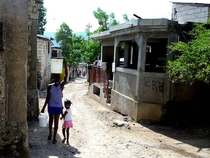 Una mujer carga con agua tras comprarla en un kiosko de Jacmel (Haití).