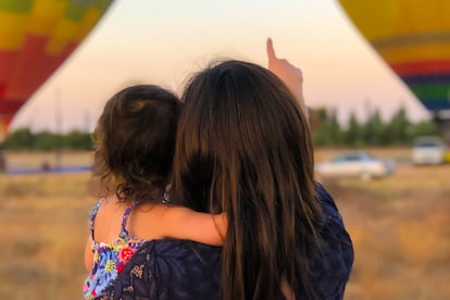 Una madre con su pequeña miran una exhibición de globos aerostáticos.