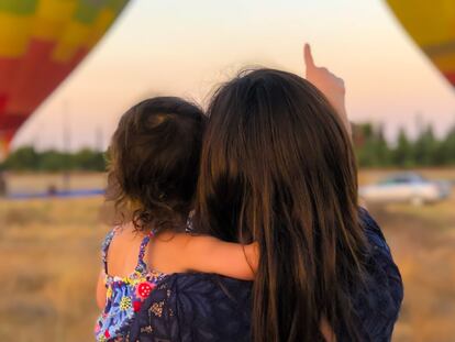 Una madre con su pequeña miran una exhibición de globos aerostáticos.