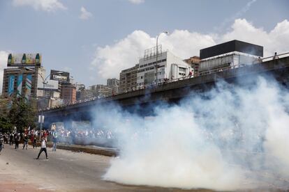 Los manifestantes se alejan del gas lacrimógeno lanzado por las fuerzas de seguridad, en Caracas.