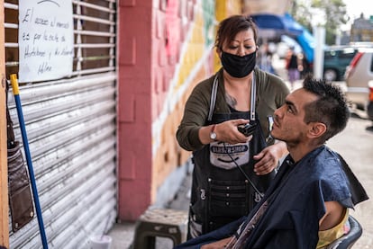 Lilia Martínez corta el cabello al  exterior del mercado Morelos, en Ciudad de México.