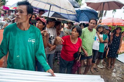 Familias en Kananga esperan bajo la lluvia la descarga del material para reconstruir sus casas: paneles de contrachapado y piezas de galvanizado para el techo.