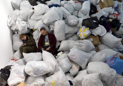 Voluntarios de un centro humanitario descansan entre bolsas de ropa donadas para los evacuados en la ciudad de Lviv, en el oeste de Ucrania, este sábado. Mijaílo Podoliak, asesor del presidente ucranio, ha pedido este sábado en su cuenta de Twitter que China tome partido y "condene la barbarie rusa" en Ucrania.